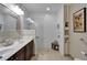 Bright bathroom showcasing double sinks, a large mirror, and a modern tiled shower with built-in shelving at 5646 Sunset Falls Dr, Apollo Beach, FL 33572