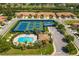 Aerial view of a community pool and tennis courts surrounded by lush landscaping in a residential neighborhood at 5646 Sunset Falls Dr, Apollo Beach, FL 33572
