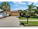Charming one-story home featuring a well-manicured lawn, palm trees, and a driveway leading to a two-car garage at 5646 Sunset Falls Dr, Apollo Beach, FL 33572