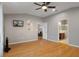 Spacious living room boasts wood floors, ceiling fan, and a tv, with access to the bathroom and another living space at 6303 Gentle Ben Cir, Wesley Chapel, FL 33544