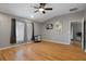 An open concept living room features wood floors, ceiling fan, and large windows with translucent curtains at 6303 Gentle Ben Cir, Wesley Chapel, FL 33544
