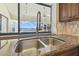 Close up of a double basin kitchen sink with granite counter tops and a view of the screened in pool at 6322 Cocoa Ln, Apollo Beach, FL 33572
