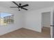 A clean and simple bedroom with a large window, ceiling fan, and laminate floors at 6508 Senegal Palm Way, Apollo Beach, FL 33572