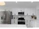 Modern kitchen with stainless steel appliances, white cabinetry and stone backsplash at 6508 Senegal Palm Way, Apollo Beach, FL 33572