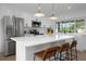 Bright white kitchen with stainless steel appliances, stone countertops, a large island with seating, and large window at 6508 Senegal Palm Way, Apollo Beach, FL 33572
