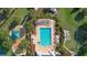 Aerial view of a beautiful community pool featuring a splashpad, lush landscape, and plenty of lounge chairs at 6555 Sparkling Way, Wesley Chapel, FL 33545