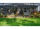 Back patio and manicured lawn with mature trees and landscaping at 6555 Sparkling Way, Wesley Chapel, FL 33545