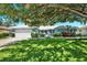 Charming single-story home with a manicured lawn, lush landscaping, and inviting curb appeal under a large tree at 7092 119Th St, Seminole, FL 33772