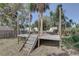 Outdoor wooden deck featuring stairs, posts, and furniture, surrounded by trees for a serene backyard experience at 7600 Drew Oak Dr, Seminole, FL 33772