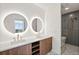 Modern bathroom featuring dual sinks, round LED mirrors, wooden cabinets, and a glass enclosed shower at 777 3Rd N Ave # 905, St Petersburg, FL 33701