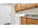 Laundry room featuring wood cabinets, granite countertops, a sink, and modern washer/dryer units at 9735 Conservation Dr, New Port Richey, FL 34655
