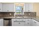 Kitchen sink with granite countertops, mosaic backsplash, stainless dishwasher, and white cabinets at 9780 Allen Rd, Lithia, FL 33547