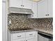 Close up of kitchen details including granite countertops, mosaic backsplash and a stainless range hood at 9780 Allen Rd, Lithia, FL 33547