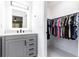 Bathroom vanity with gray cabinet and mirror, next to a walk-in closet with a variety of clothing at 3254 Great Neck St, Port Charlotte, FL 33952