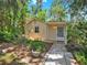 A charming guest house surrounded by trees and lush plantings features a covered front porch and stone walkway at 1141 Myrtle Rd, Valrico, FL 33596