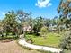 Lush yard featuring a long walkway, verdant grass, mature trees, and an inviting exterior of the home in the background at 1141 Myrtle Rd, Valrico, FL 33596