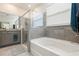 Well-lit bathroom features a tub with shower and gray tiling and a light gray vanity at 12401 Shining Willow St, Riverview, FL 33579
