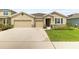 Inviting home featuring a 3-car garage, stone accents, manicured lawn, and a welcoming entrance at 12401 Shining Willow St, Riverview, FL 33579