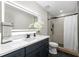 Modern bathroom featuring a sleek vanity with a lighted mirror and a tiled shower with black fixtures at 12804 Bert Pl, Tampa, FL 33625