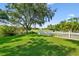 Spacious backyard with manicured lawn, a white picket fence, and views of a golf course beyond at 13028 Prestwick Dr, Riverview, FL 33579