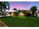 Charming single-story home featuring a well-manicured lawn and lush tropical landscaping at dusk at 13028 Prestwick Dr, Riverview, FL 33579