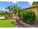 Detail of the home's manicured landscaping featuring a well-maintained lawn, tropical plants, and attractive mulch beds at 13028 Prestwick Dr, Riverview, FL 33579