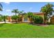 Charming single-story home featuring a well-manicured lawn and lush tropical landscaping, including palm trees at 13028 Prestwick Dr, Riverview, FL 33579