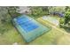 Aerial view of a fenced tennis court alongside a shuffleboard court at 13205 Cypress Hill Dr, Hudson, FL 34669