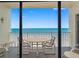 Beach view from a balcony with a table and chairs at 13500 Gulf Blvd # 706, Madeira Beach, FL 33708