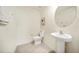 A well-lit powder room featuring modern fixtures, a pedestal sink, and a round mirror at 13727 Whiskey Daisy Dr, Dade City, FL 33525