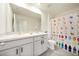 Bright bathroom featuring a double vanity with white cabinets and a colorful, -friendly shower curtain at 13727 Whiskey Daisy Dr, Dade City, FL 33525