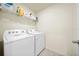 Bright laundry room features a white washer and dryer, with a wire shelf for organized storage at 13727 Whiskey Daisy Dr, Dade City, FL 33525