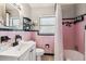 Quaint bathroom with pink tile, modern black fixtures, and great storage at 13920 Berkowitz Ave, Hudson, FL 34667