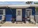 Welcoming front entrance to a blue home with a white door, awning, and potted plants, creating a cozy curb appeal at 13920 Berkowitz Ave, Hudson, FL 34667