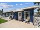 Inviting single-story blue home with a bright white awning, chairs, and potted plants on the front patio at 13920 Berkowitz Ave, Hudson, FL 34667