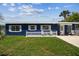 Charming blue single-story home featuring a well-manicured lawn and a cozy front patio with white picket fence at 13920 Berkowitz Ave, Hudson, FL 34667