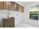 Bright laundry room with stainless steel sink, wood cabinets, and a window offering natural light at 14170 Fennsbury Dr, Tampa, FL 33624
