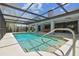 A screened in pool features clean blue water and a large step-down hot tub at 14170 Fennsbury Dr, Tampa, FL 33624
