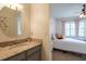 A bathroom vanity with granite countertop and a bedroom with a floral wallpaper in the background at 16170 Colchester Palms Dr, Tampa, FL 33647