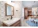 Elegant powder room with a wood vanity, patterned wallpaper, and view into the eat in kitchen area at 16170 Colchester Palms Dr, Tampa, FL 33647
