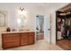 Bathroom with a light wood vanity, cream countertop, an oval mirror, and a walk-in closet with custom shelving at 16170 Colchester Palms Dr, Tampa, FL 33647