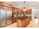A kitchen with stainless steel refrigerator, brown cabinets, granite countertop and kitchen island at 16170 Colchester Palms Dr, Tampa, FL 33647