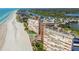 Aerial view showcasing beachfront buildings, a pool, lush landscaping, and the beautiful coastline along the ocean at 17920 Gulf Blvd # 208, Redington Shores, FL 33708