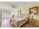 Bedroom with a ceiling fan, pale yellow walls, balcony access, and light wood-style laminate flooring at 17920 Gulf Blvd # 208, Redington Shores, FL 33708