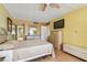 Bedroom with a mounted TV, pale yellow walls, wood-style laminate flooring, and adjacent bathroom at 17920 Gulf Blvd # 208, Redington Shores, FL 33708