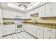 Well-lit kitchen with white cabinets, granite countertops, white appliances, and tiled floor at 17920 Gulf Blvd # 208, Redington Shores, FL 33708