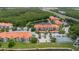 Wide aerial view of the condo complex with tennis court, surrounded by greenery and a lake at 18107 Peregrines Perch Pl # 6303, Lutz, FL 33558
