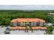 Aerial view shows the condo building with a red tile roof and private balconies, surrounded by lush greenery at 18107 Peregrines Perch Pl # 6303, Lutz, FL 33558