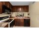 Galley kitchen featuring dark wood cabinetry, appliances, and views of living space at 1905 Oyster Catcher Ln # 924, Clearwater, FL 33762
