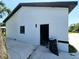 Exterior view of the home featuring a fresh white exterior with black trim and a well-maintained concrete yard at 20295 Lorenzo Ave, Port Charlotte, FL 33952